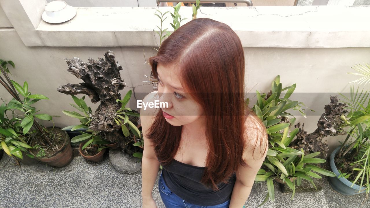 High angle view of young woman standing by potted plants