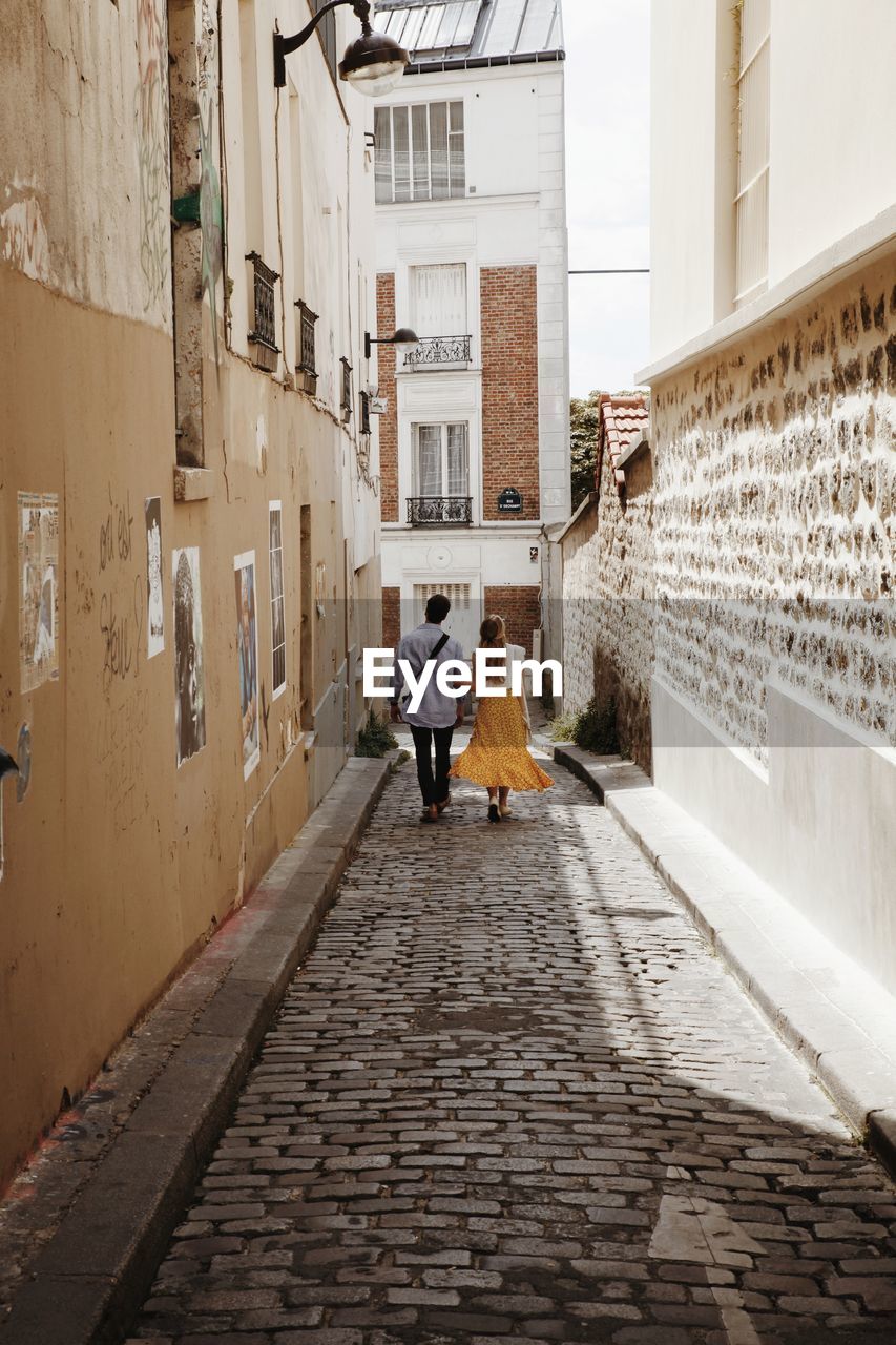 Rear view of woman walking on street amidst buildings