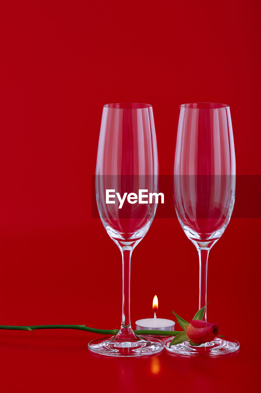 Champagne flutes against glass against red background