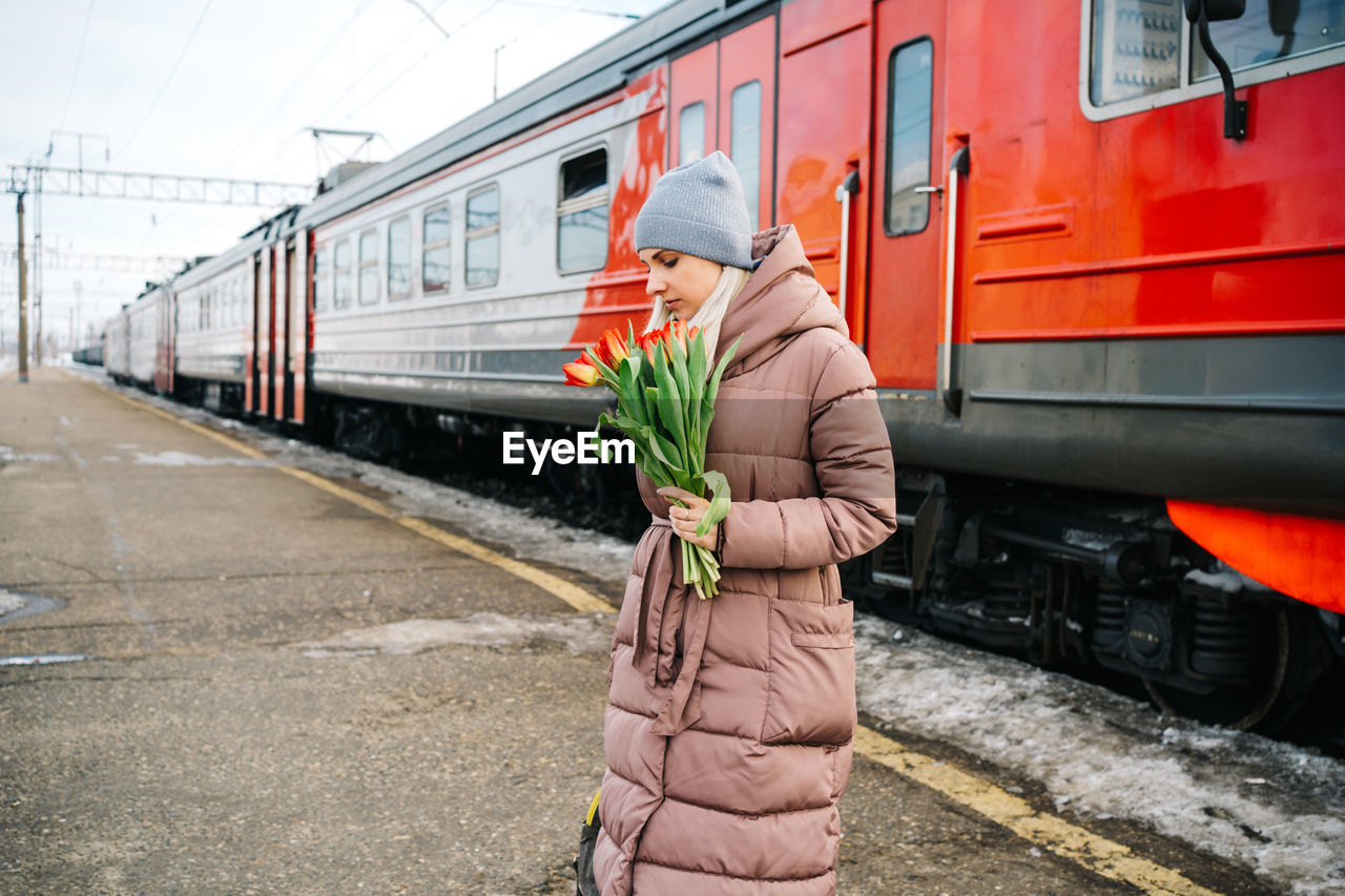 Girl with a bag and flowers on the platform of the station