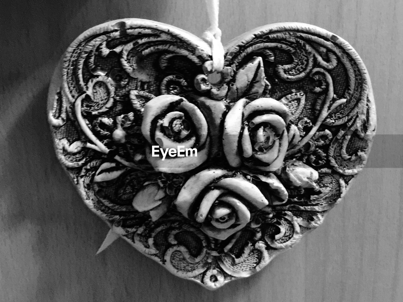 Close-up of rose in heart shape decoration against wall at home