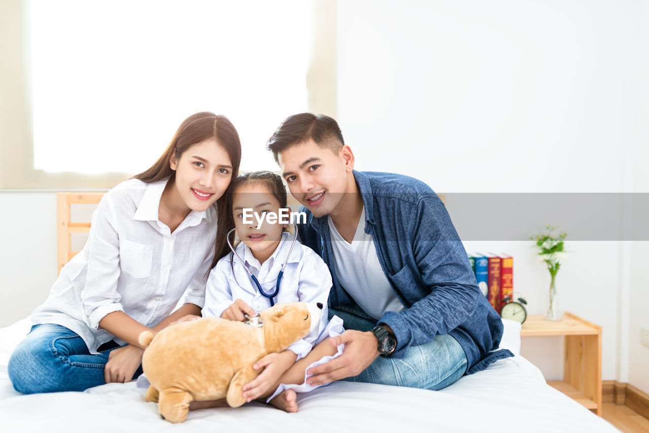 Portrait of family sitting on bed at home