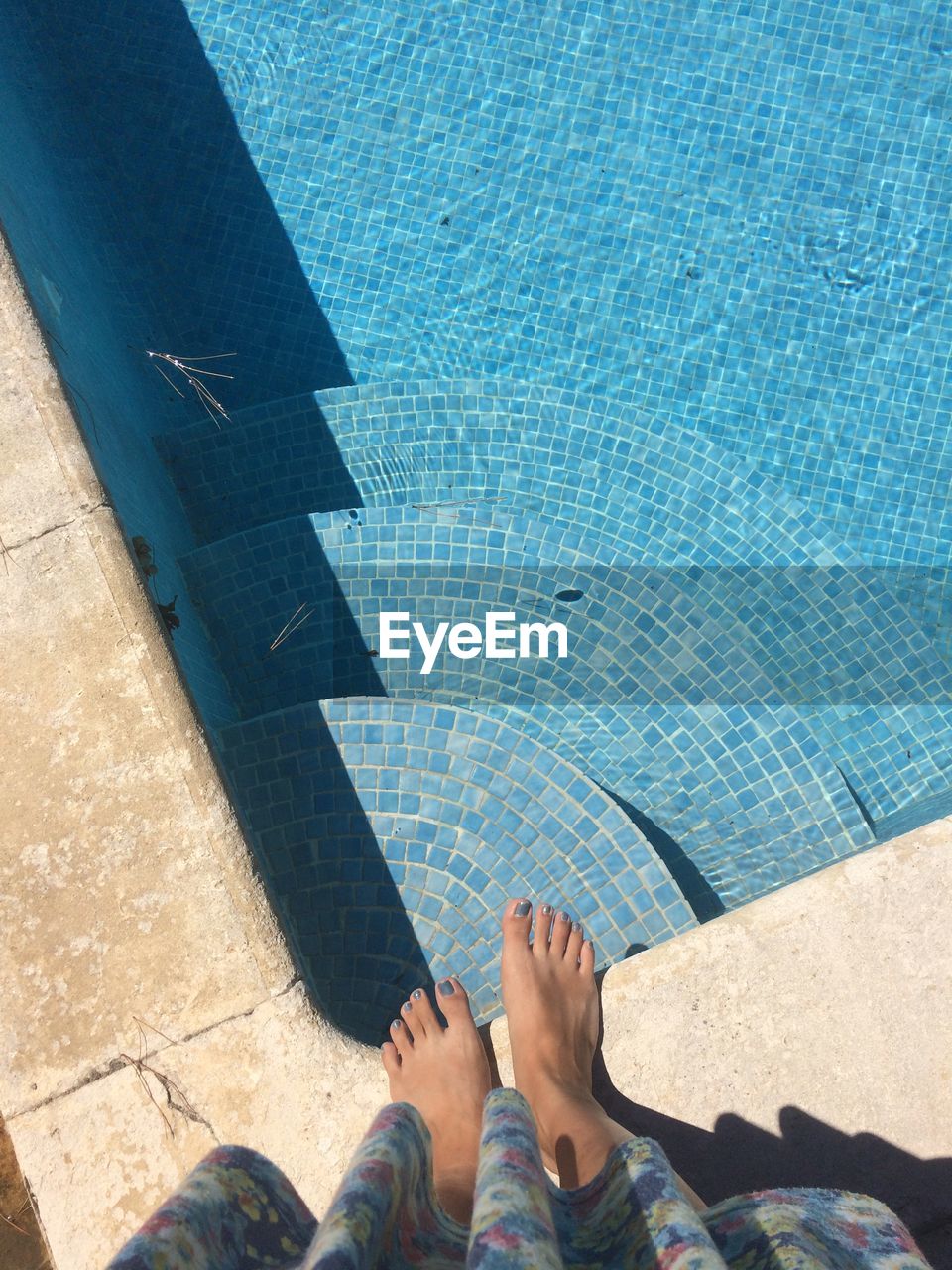 Low section of woman standing against swimming pool