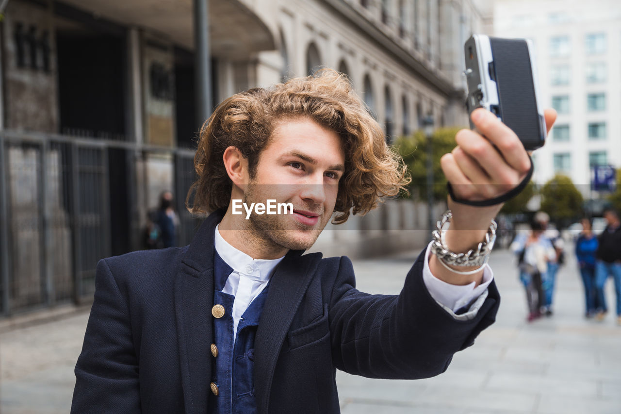 PORTRAIT OF YOUNG MAN USING SMART PHONE