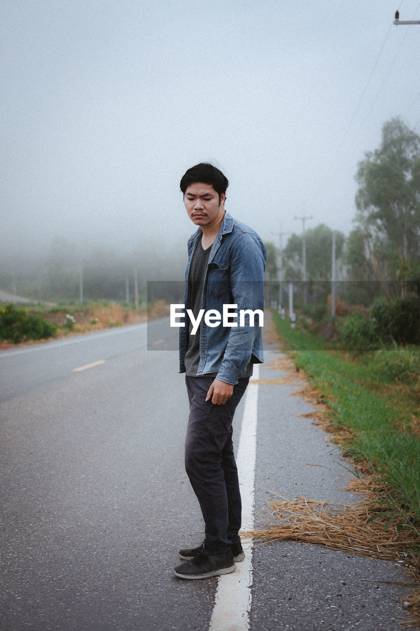 Full length portrait of young man standing on road