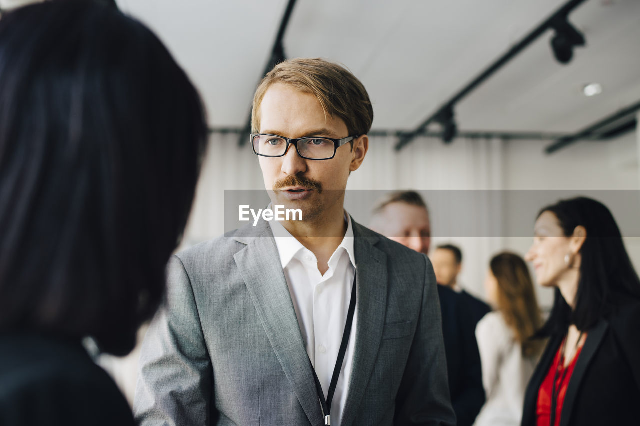 Male coworker talking to female colleague in office