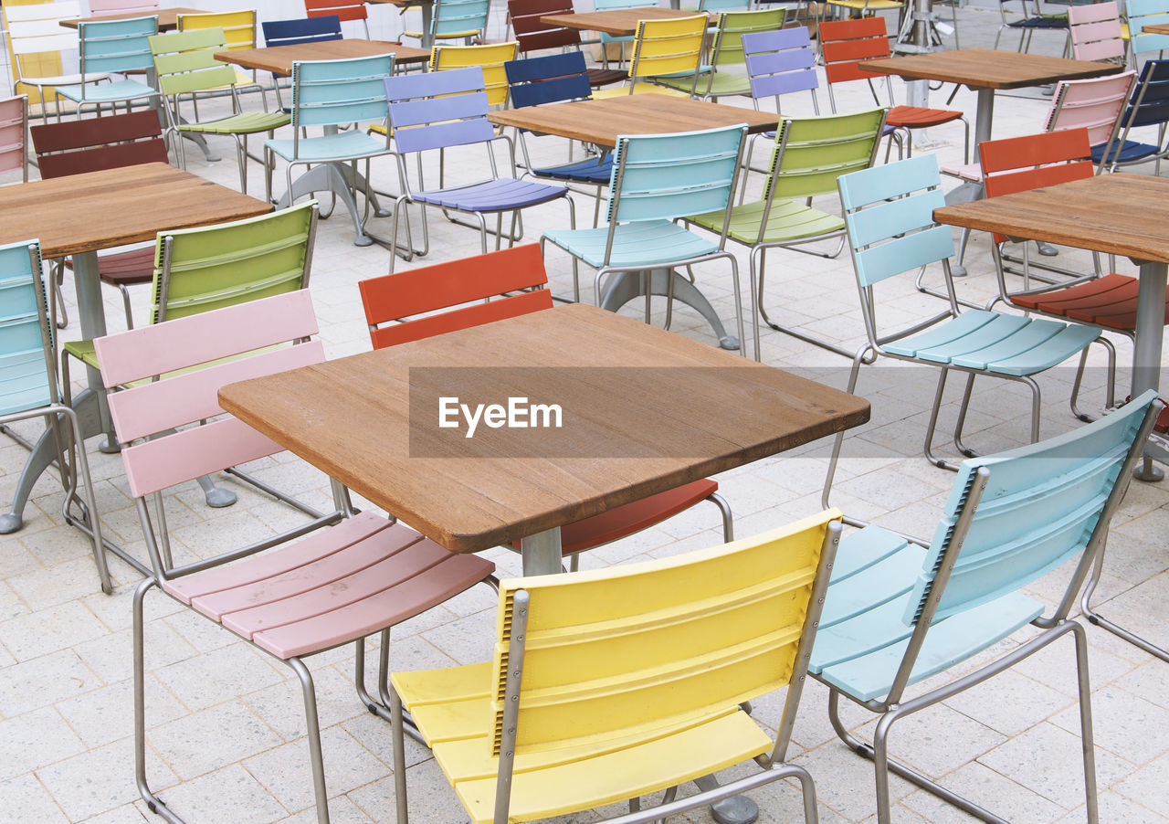 Empty deserted street cafe or outdoor restaurant tables with multicolored chairs 