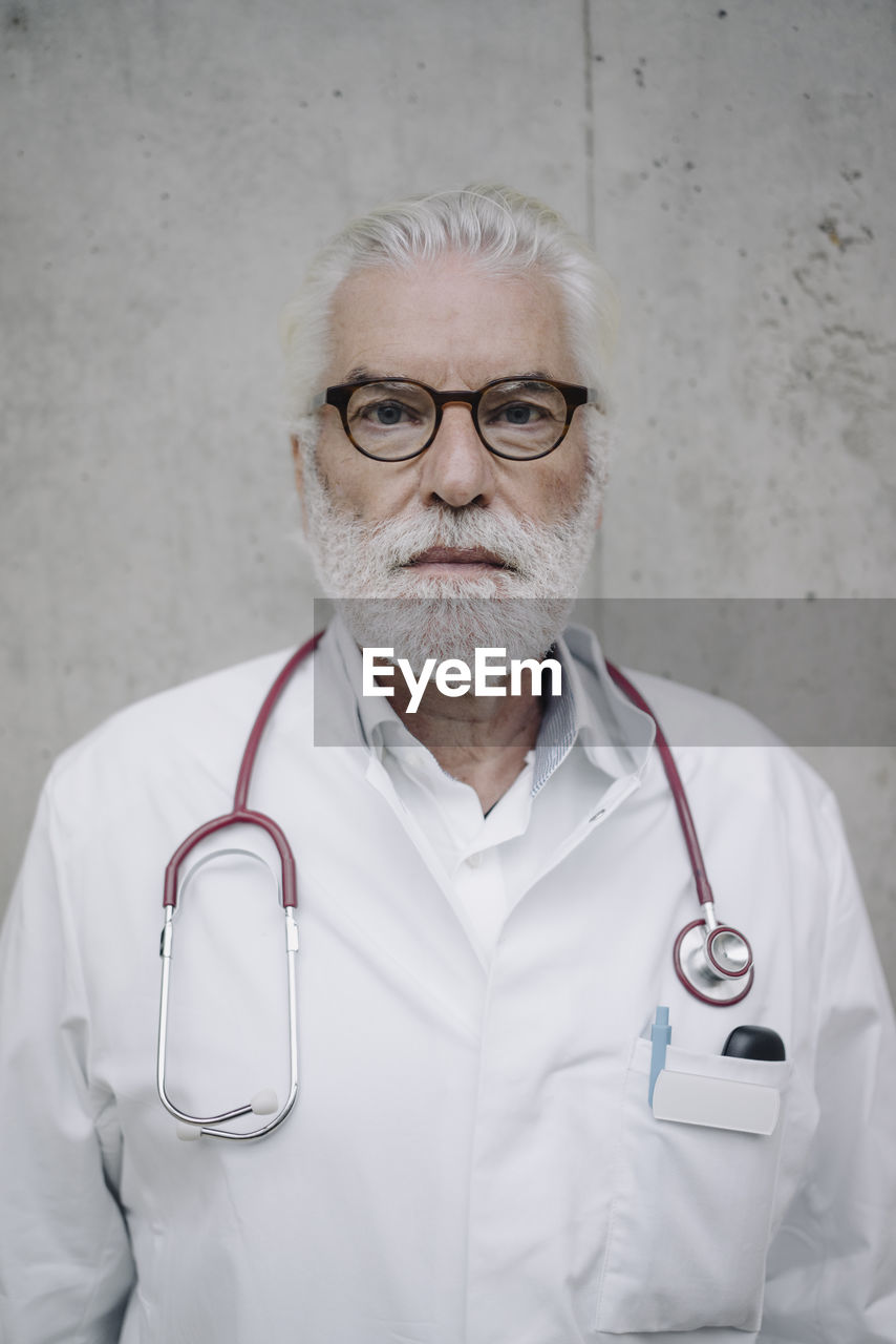 Portrait of a serious doctor at a concrete wall