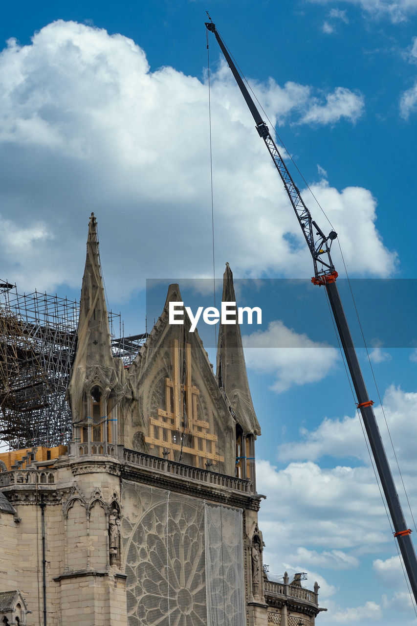 LOW ANGLE VIEW OF CRANE AGAINST BUILDING