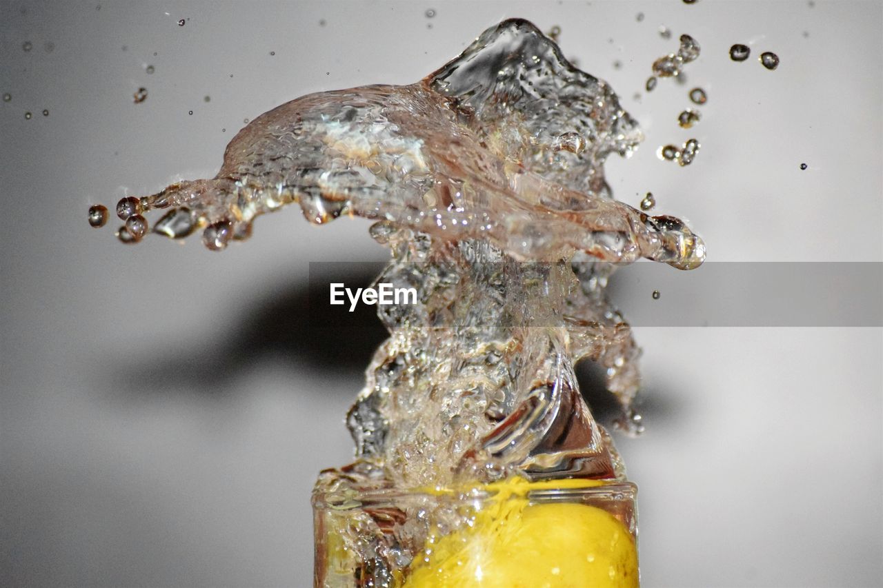 Close-up of water splashing in glass with lemon