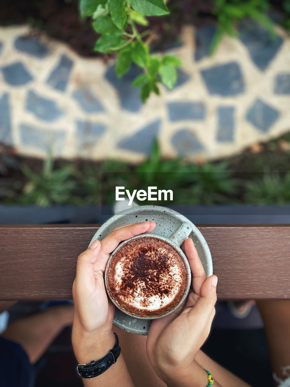 HIGH ANGLE VIEW OF HAND HOLDING COFFEE CUP AT HOME