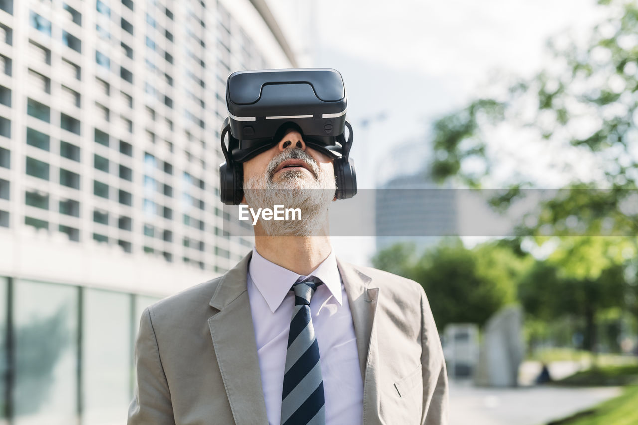 Businessman with virtual reality simulator standing in front of building