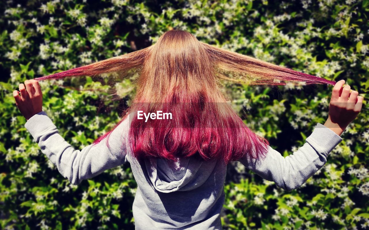 REAR VIEW OF WOMAN STANDING BY PLANT