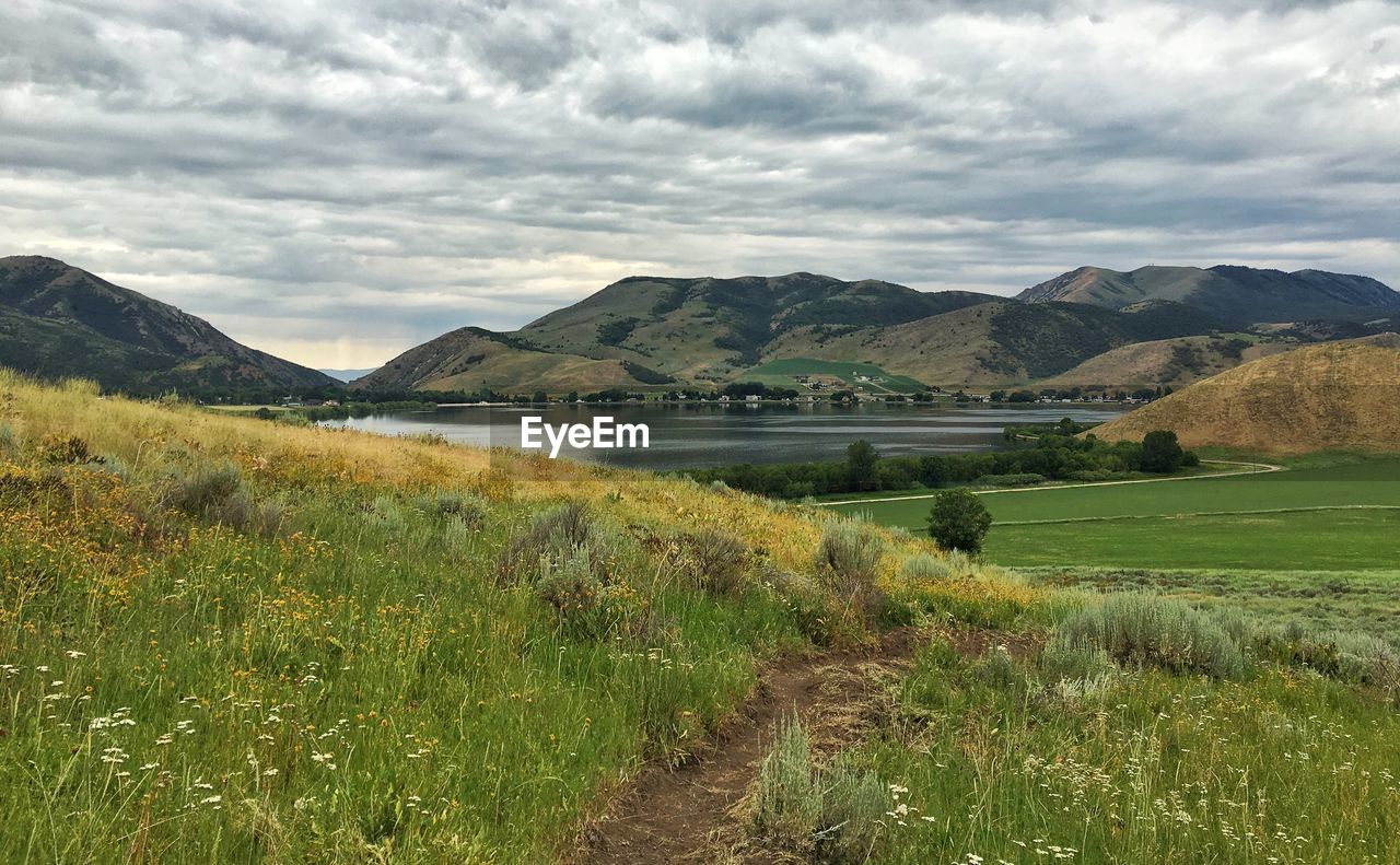 Scenic view of lake and mountains against cloudy sky