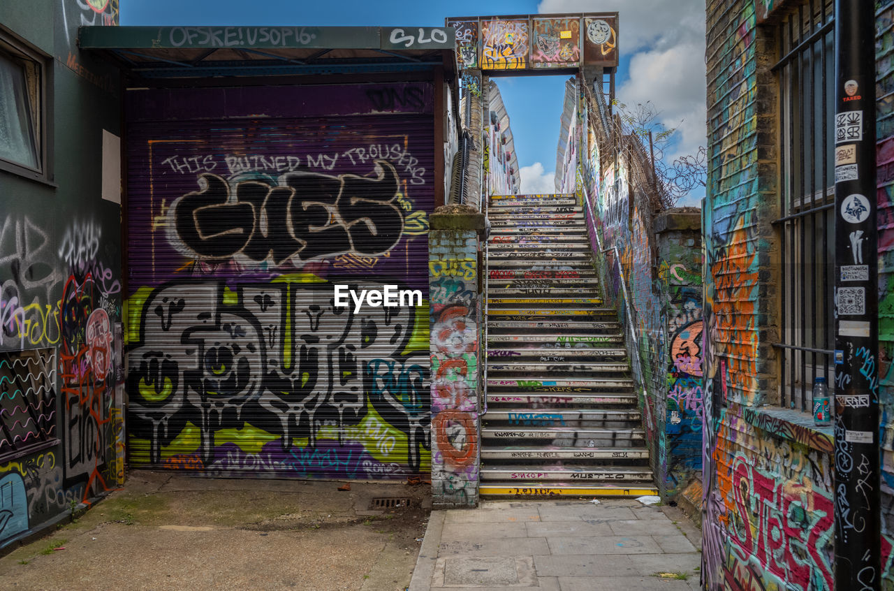 urban area, graffiti, architecture, street, art, road, built structure, multi colored, street art, neighbourhood, creativity, building exterior, city, no people, text, building, wall - building feature, communication, day, vandalism, outdoors, entrance