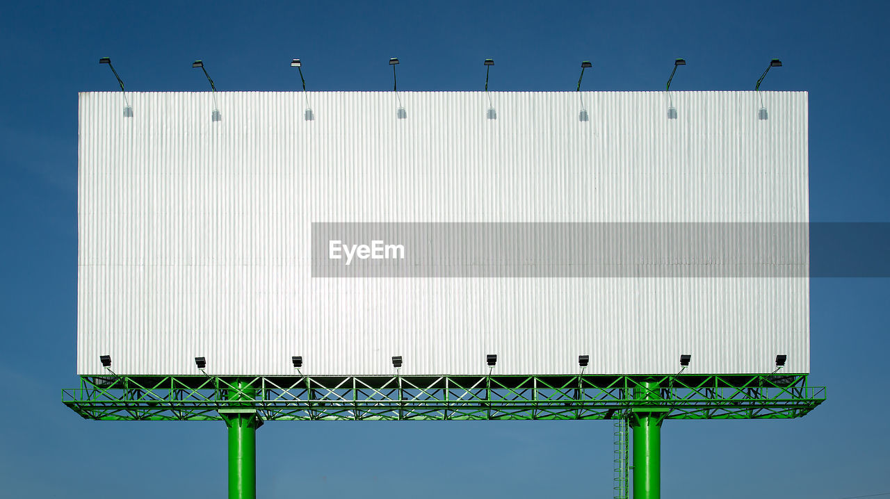 LOW ANGLE VIEW OF BIRD PERCHING ON METAL STRUCTURE AGAINST SKY