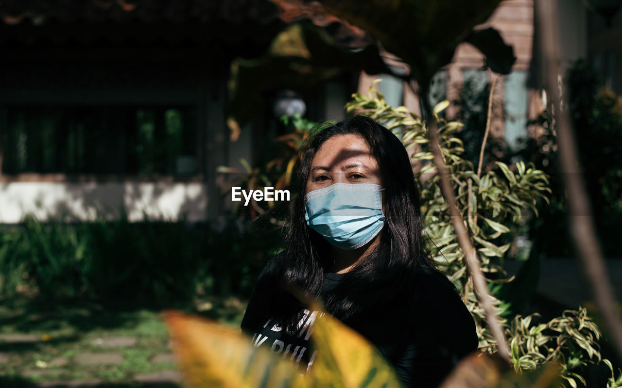 Portrait of young woman outdoors, wearing medical face mask