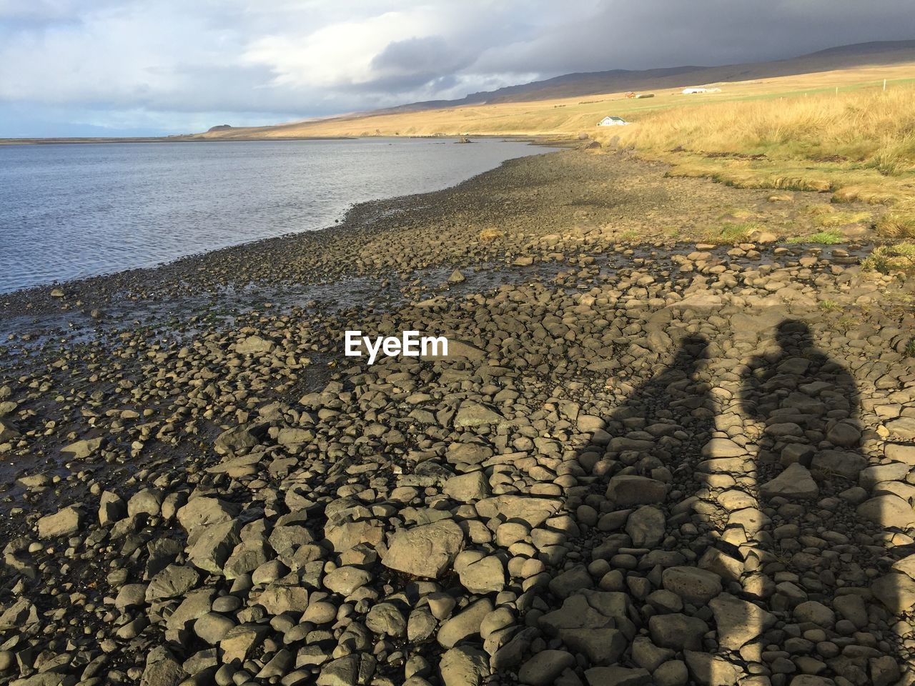 Shadow of pebbles on beach against sky