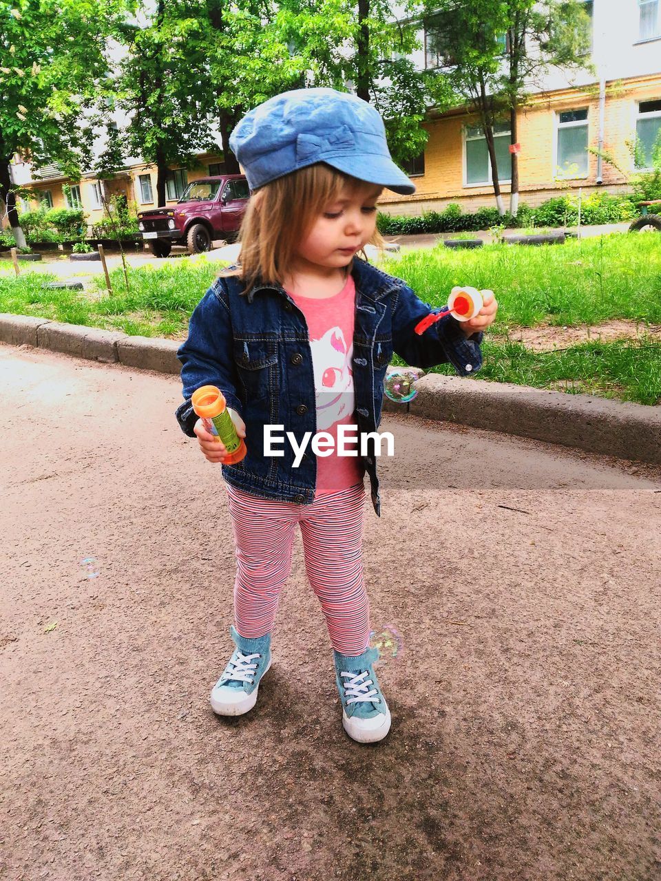 Cute girl making bubbles while standing on footpath