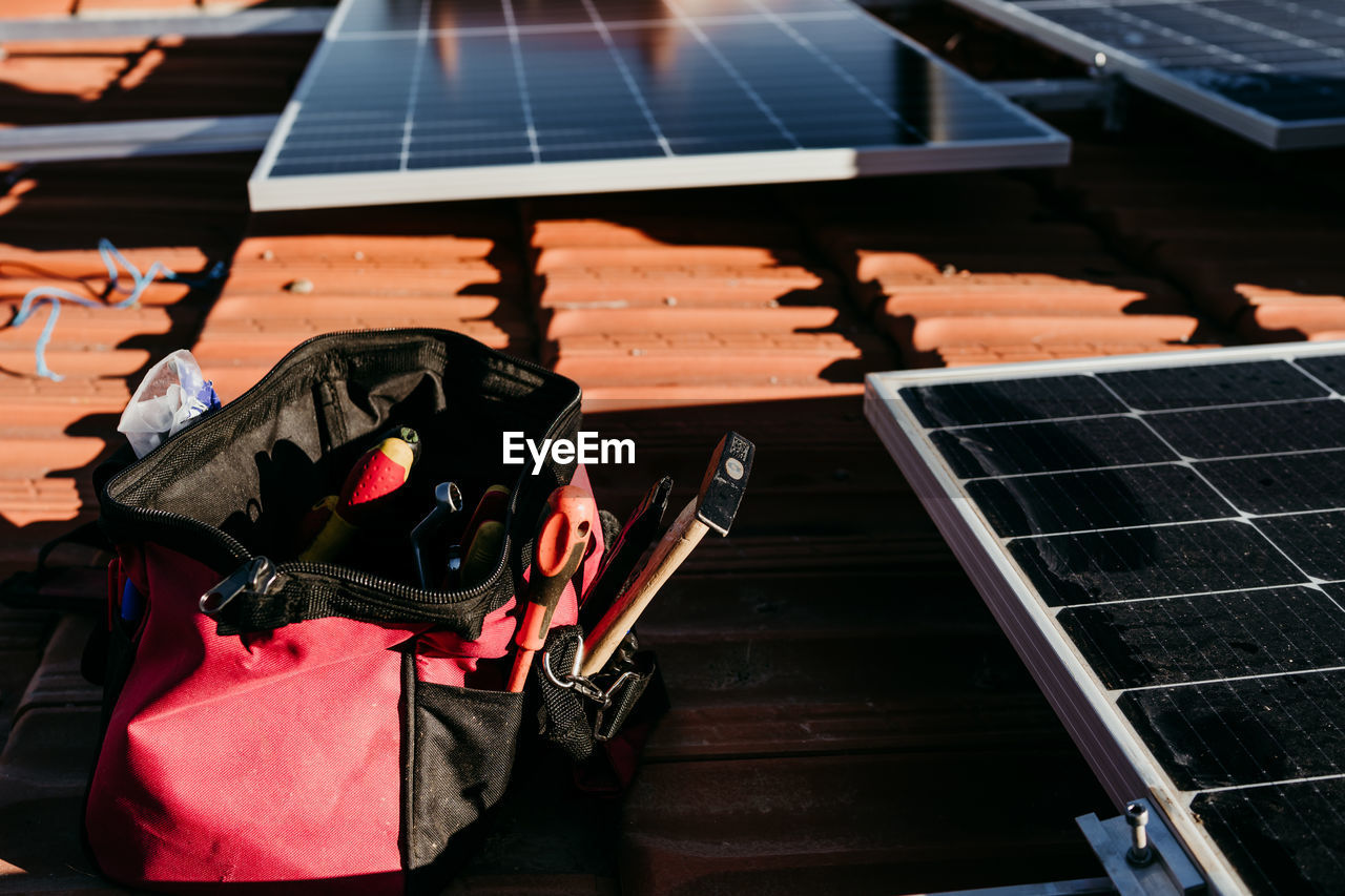 Bag of technician tools and solar panel on roof during sunrise.renewable energies and green energy