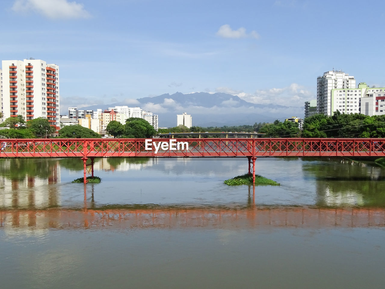 Bridge over river by buildings in city against sky