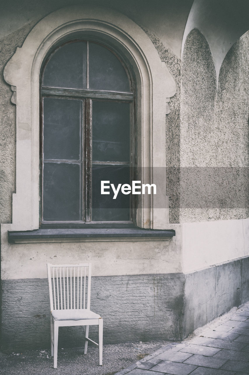 Empty chair against window of house