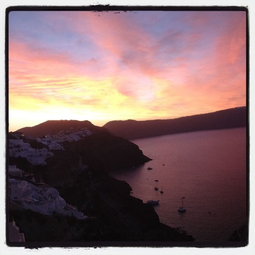 Rocks by sea against scenic sky at dusk