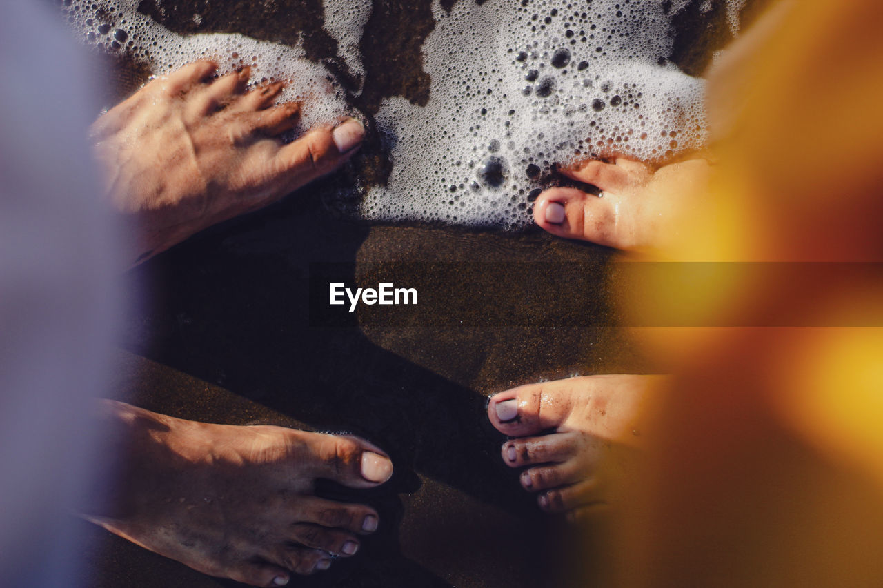 High angle view of people foot in water