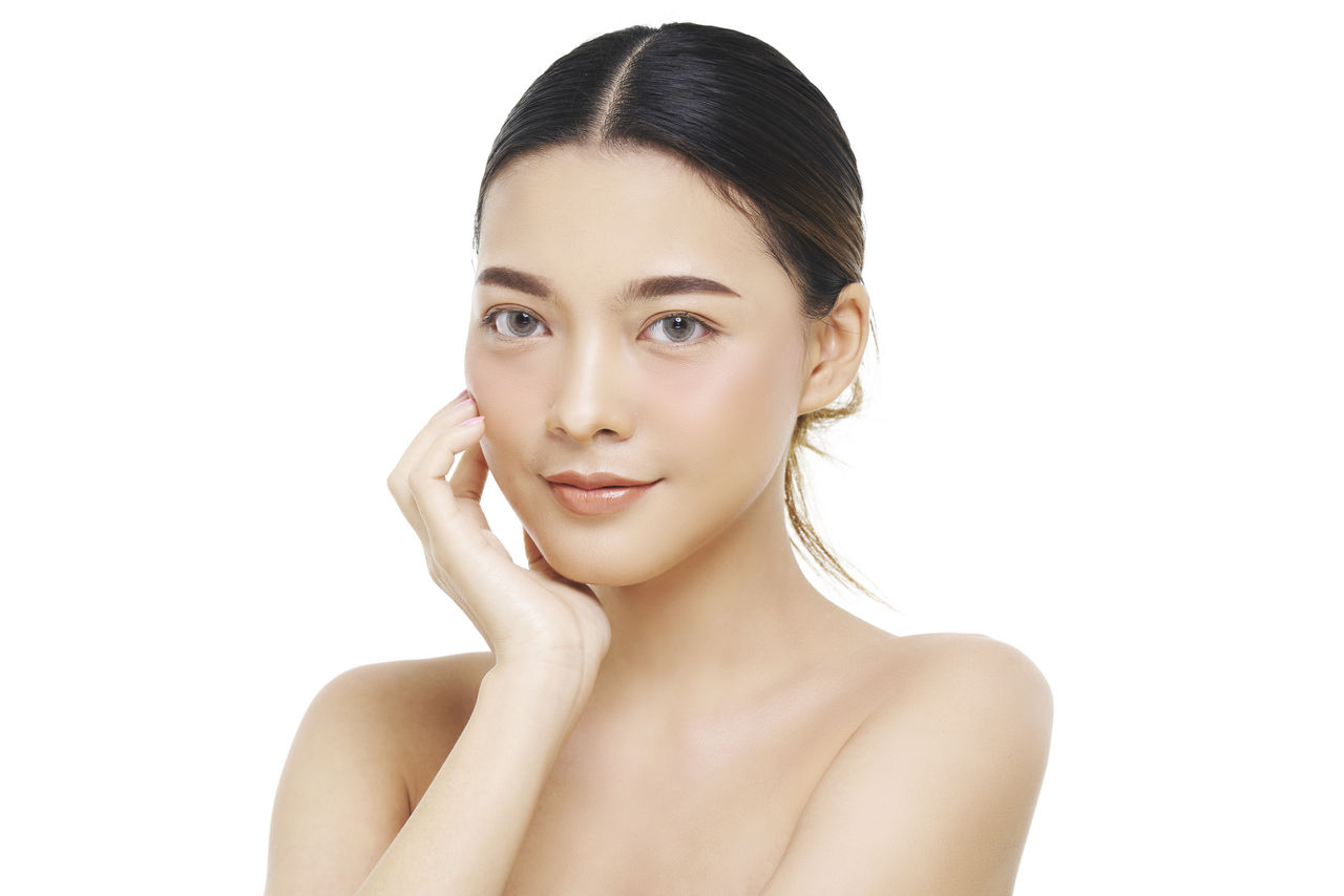 Close-up portrait of shirtless young woman over white background