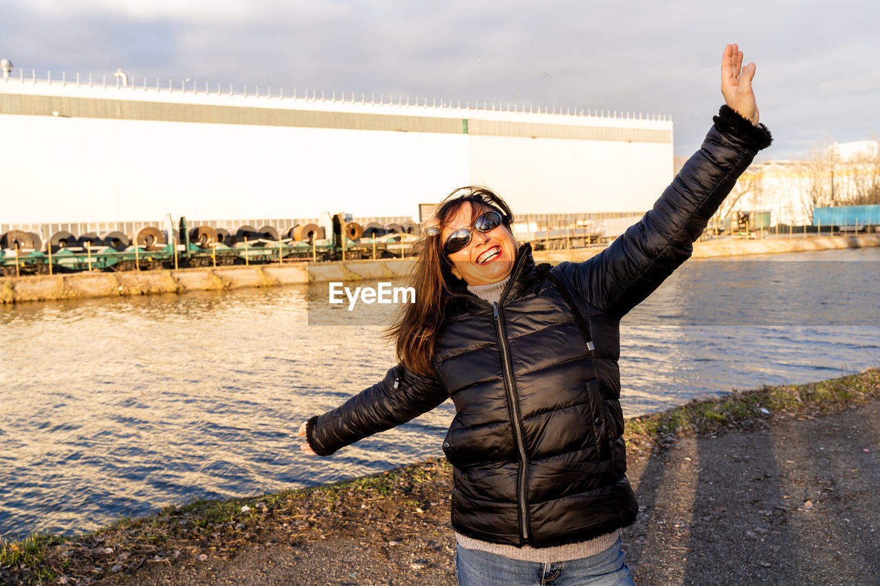 Middle aged woman wearing winter clothes taking fun by a river - people in recreation concept