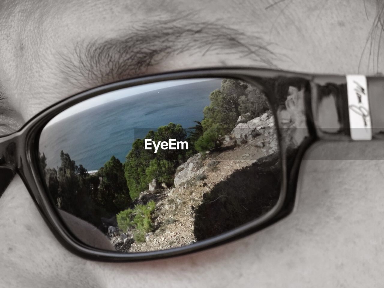Reflection of trees and blue sea in sunglasses 