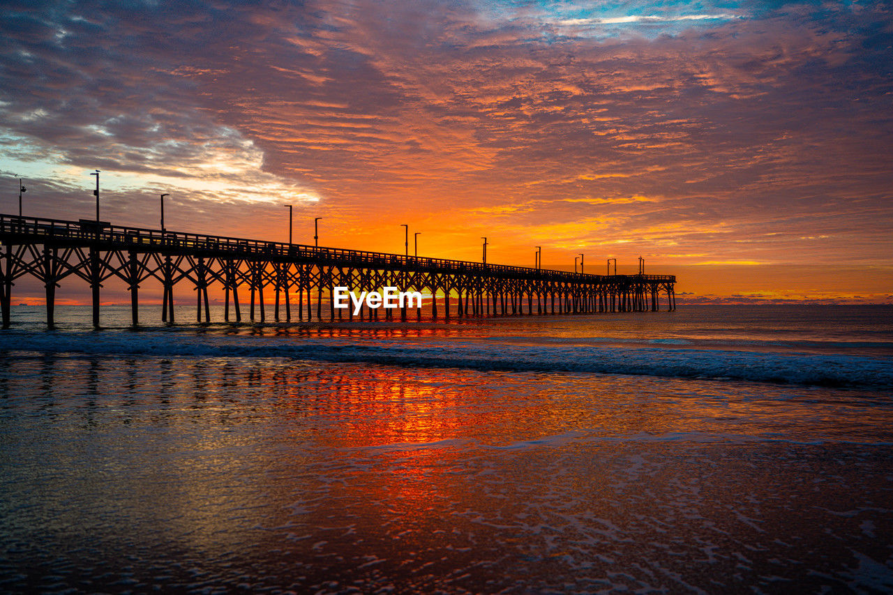 sky, water, sunset, reflection, pier, horizon, dusk, cloud, architecture, sea, evening, built structure, nature, beauty in nature, afterglow, scenics - nature, ocean, beach, land, sunlight, bridge, orange color, no people, wave, outdoors, tranquility, travel destinations, transportation, environment, dramatic sky, coast, city, travel, landscape, business finance and industry