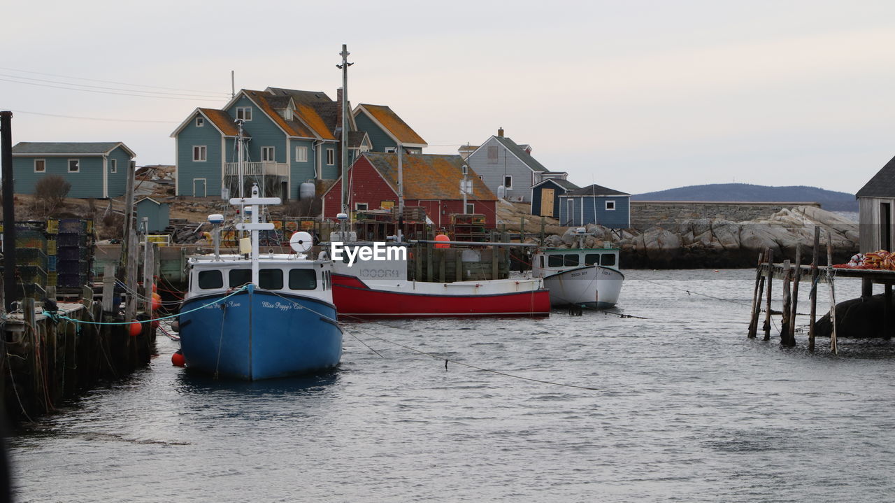 BOATS MOORED AT HARBOR AGAINST HOUSES