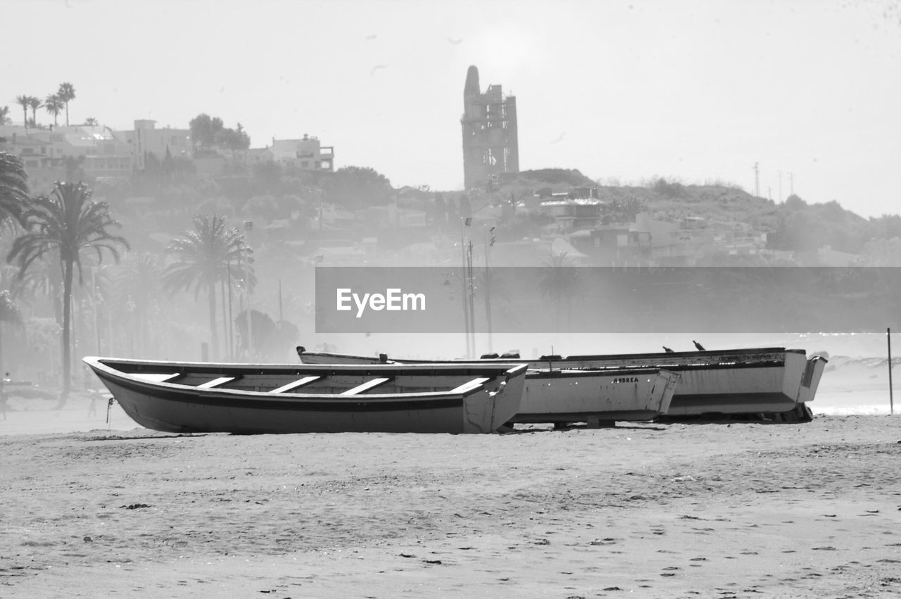 BOAT MOORED ON BEACH AGAINST SKY