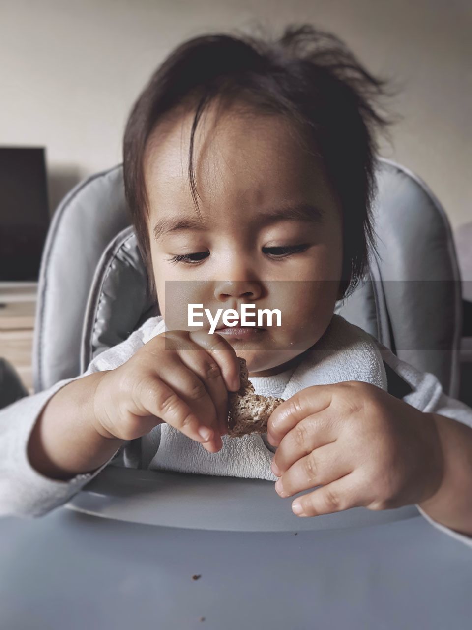 Close-up of cute baby girl holding food at home