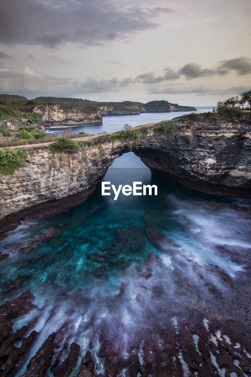 Scenic view of rock formation in sea against sky