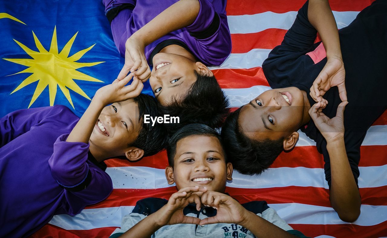 Portrait of happy friends lying on malaysian flag