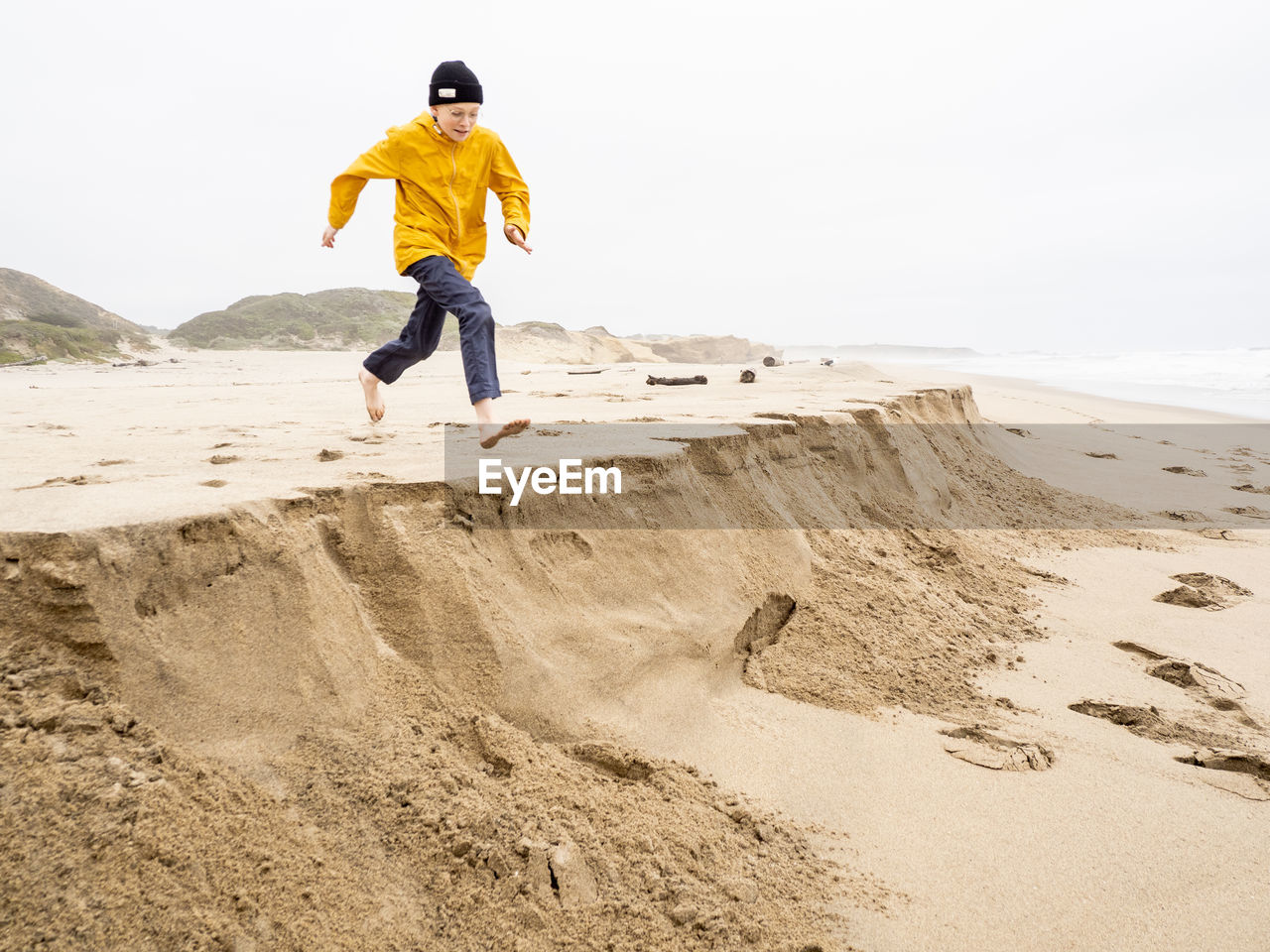 Young person running toward sandy ledge at california beach