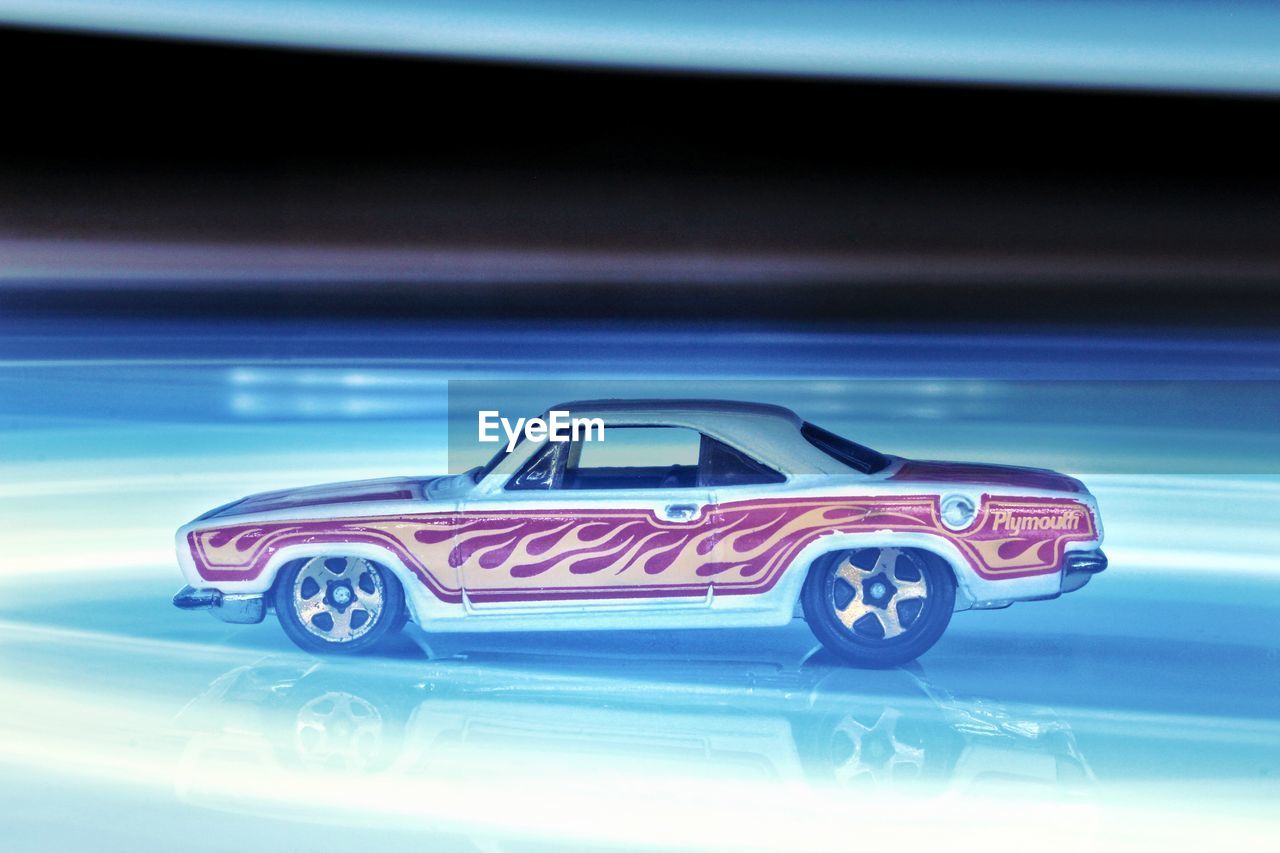 CLOSE-UP OF TOY CAR AGAINST ILLUMINATED BLUE BACKGROUND