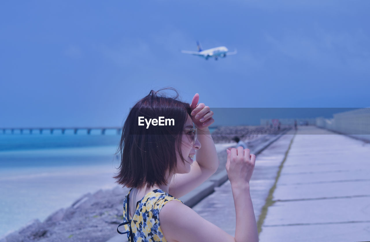 Portrait of woman against blue sea against sky