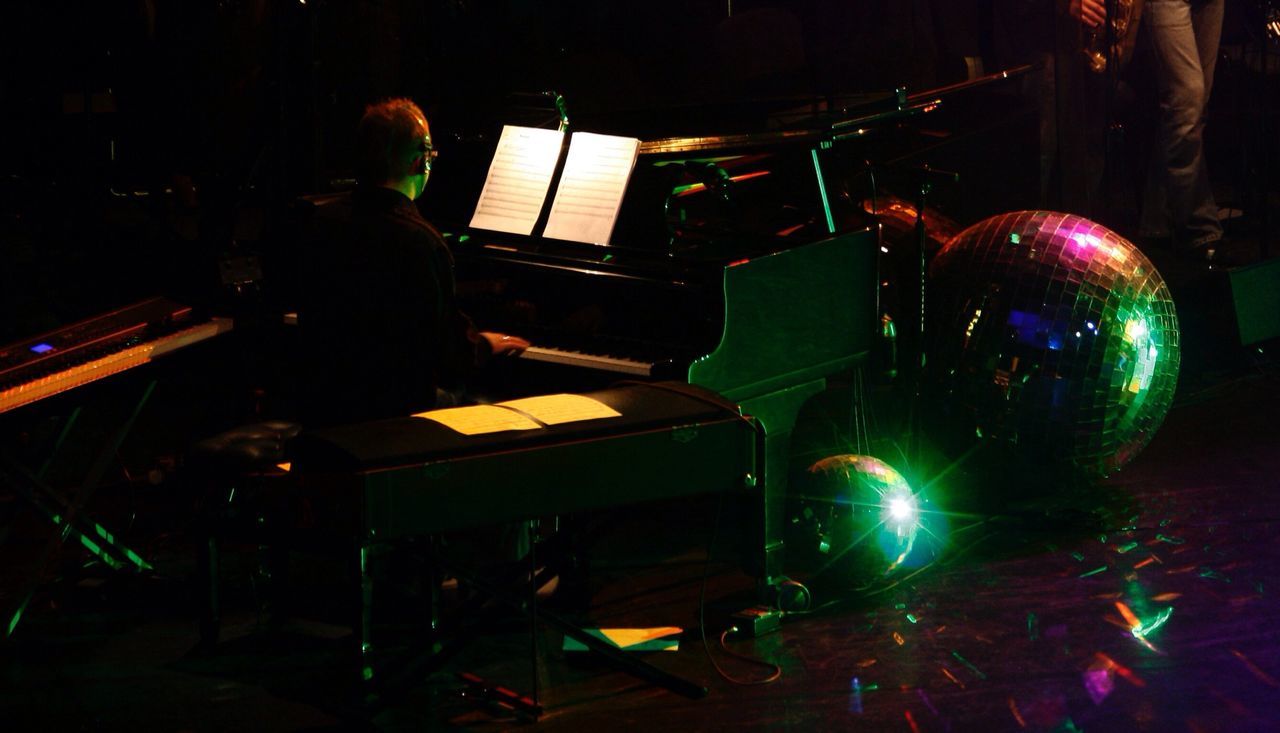 Rear view of man playing piano on stage