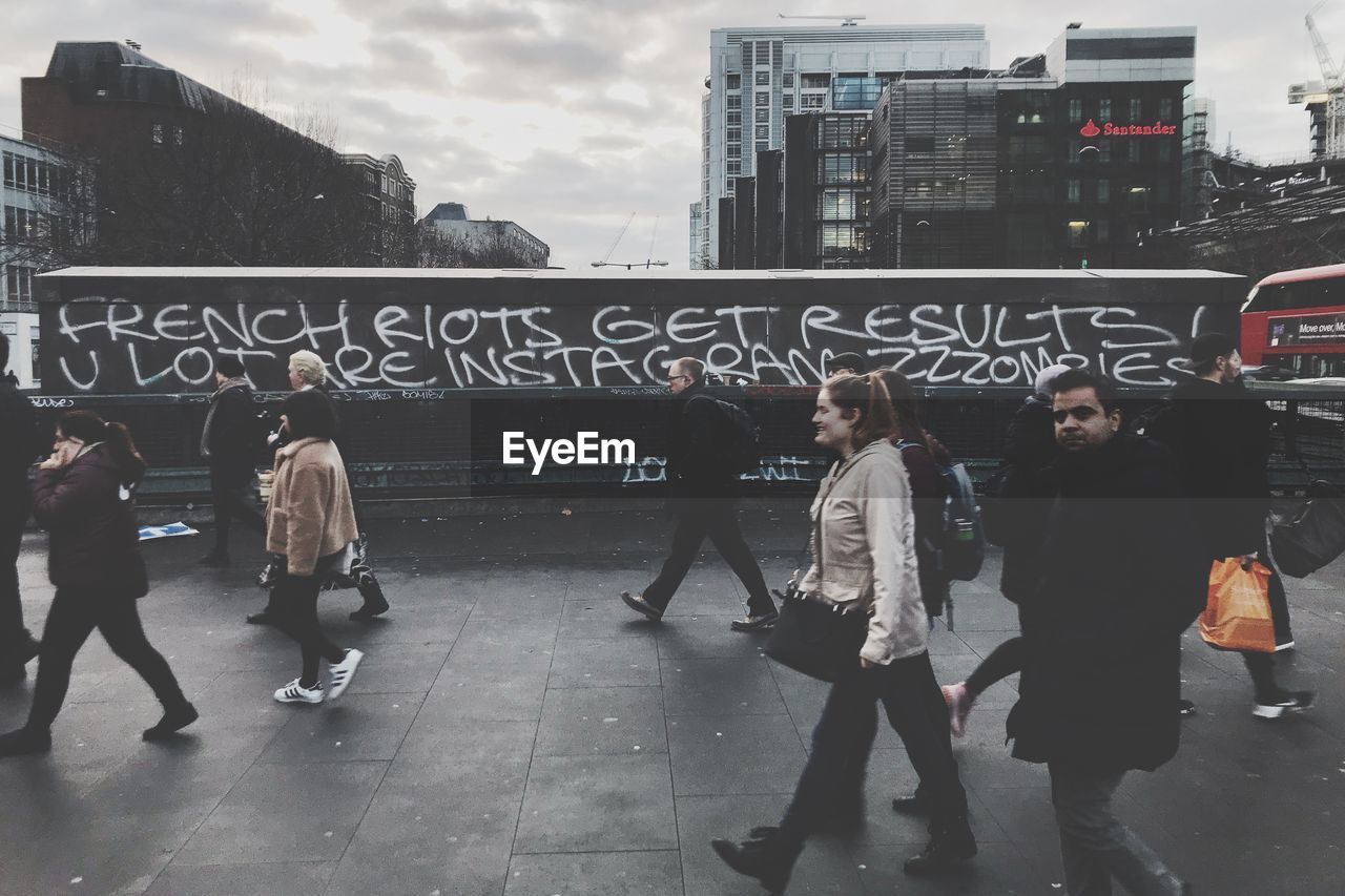 GROUP OF PEOPLE WALKING IN FRONT OF BUILDING