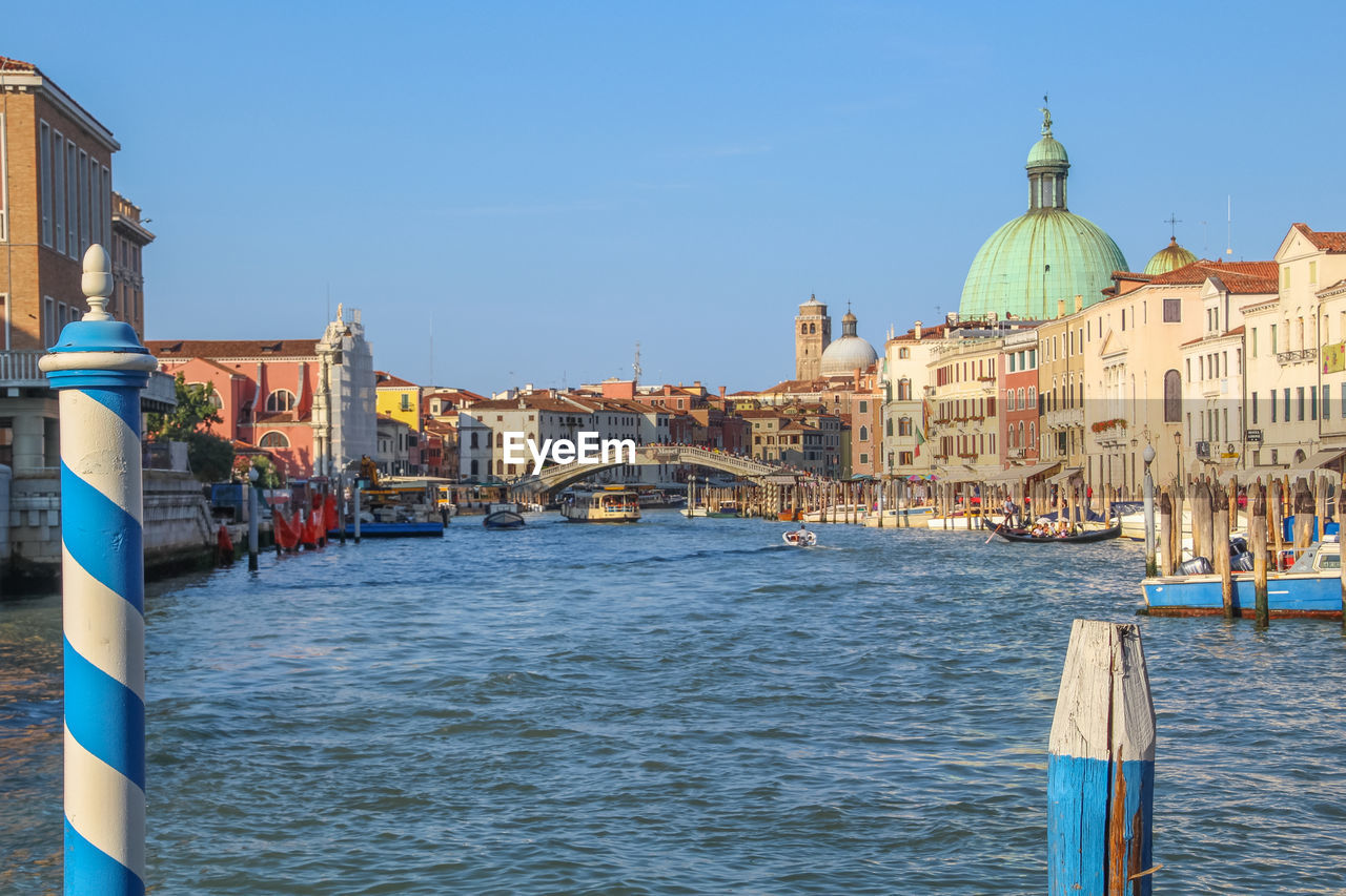 Canal amidst buildings against clear sky