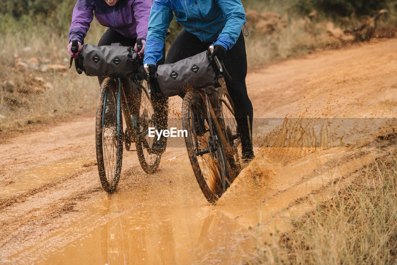 People in protective helmet and colorful jacket riding bikes in forest during bike packing adventure