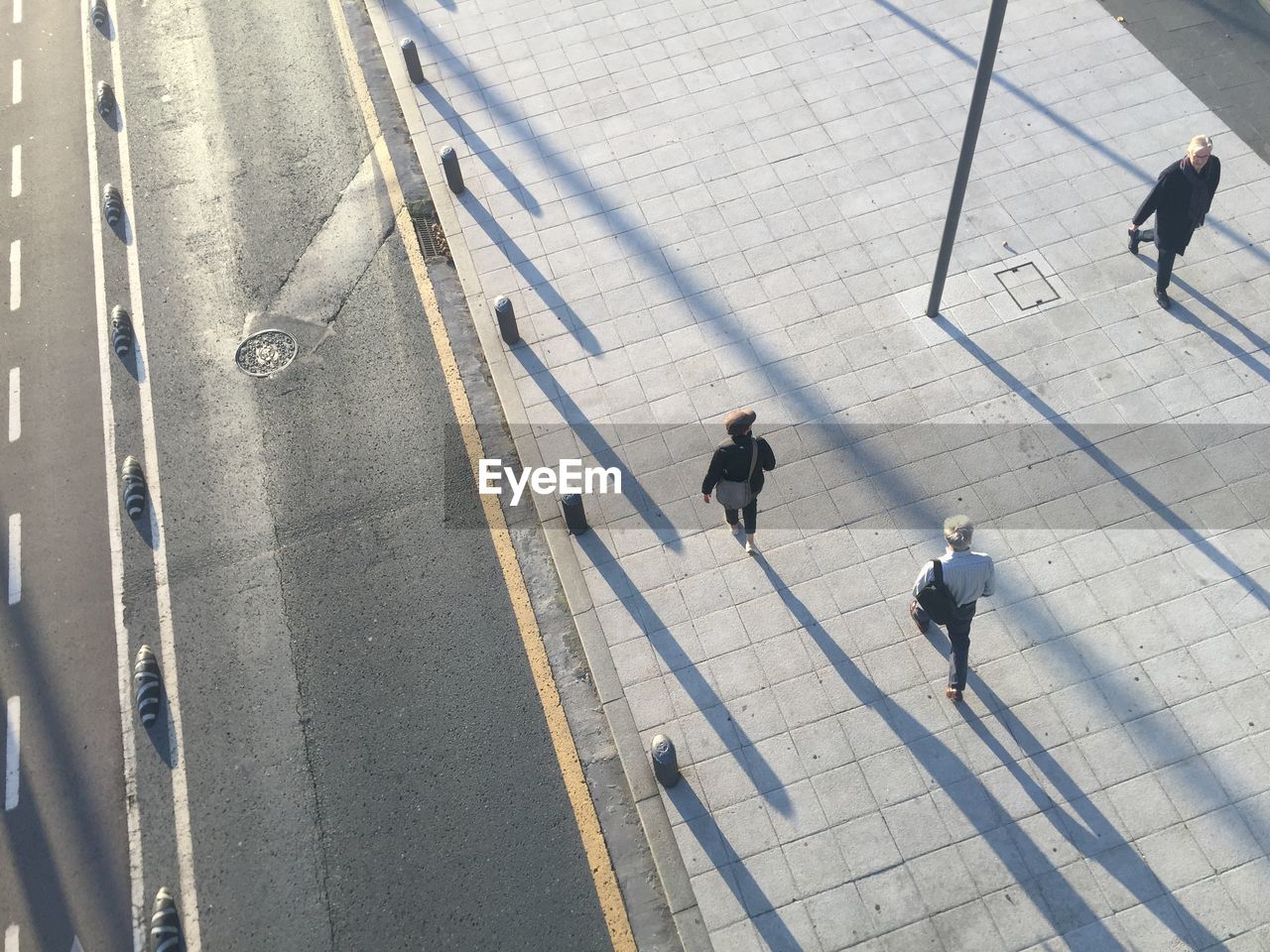 high angle view, men, group of people, walking, city, day, transportation, architecture, shadow, adult, sunlight, full length, street, road, lifestyles, sign, line, outdoors, lane, women, road marking, city life, nature, motion, group, small group of people, travel