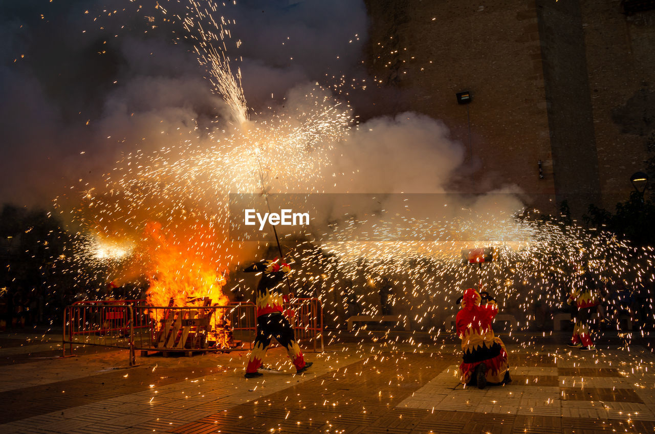 fireworks, night, celebration, motion, arts culture and entertainment, group of people, event, exploding, firework display, firework - man made object, city, street, illuminated, nature, tradition, crowd, burning, outdoors, men, architecture, large group of people, fire, traditional festival