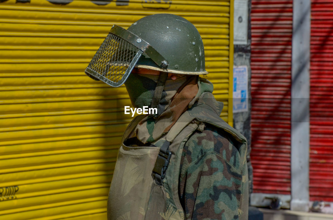 Close-up of army soldier against store shutter