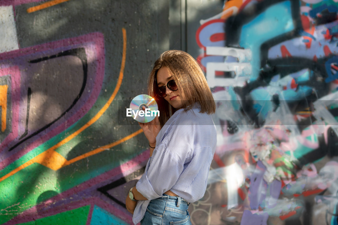 Full length of woman standing against graffiti wall