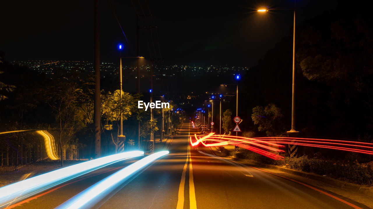 ILLUMINATED LIGHT TRAILS ON STREET AT NIGHT