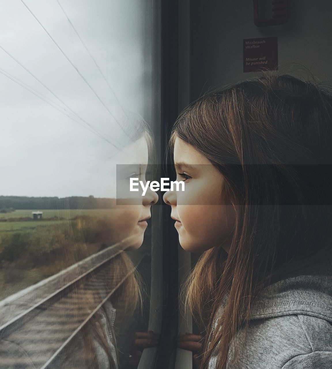 SIDE VIEW OF WOMAN LOOKING THROUGH WINDOW